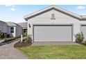 Single-story home features a spacious gray garage door, manicured lawn, and brick paved walkway at 25973 Bimini Sands Ct, Englewood, FL 34223