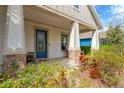 Cozy front porch with stone accents, comfortable seating, and a welcoming blue front door at 4127 Broad Porch Run, Land O Lakes, FL 34638