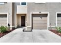 Beige townhouse featuring a one car garage, front door, rock landscaping and a well maintained lawn at 708 Barclay Wood Dr, Ruskin, FL 33570