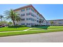 Well-maintained condo building featuring a manicured lawn, palm trees, and ample parking at 9950 62Nd N Ter # 319, St Petersburg, FL 33708
