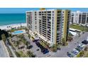 A beautiful high-rise condo building boasts a parking lot, palm trees, and a pool near the ocean at 1480 Gulf Blvd # 401, Clearwater Beach, FL 33767