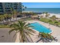 An aerial view of the community pool showcasing crystal clear water, lounge chairs, and palm trees at 1480 Gulf Blvd # 401, Clearwater Beach, FL 33767