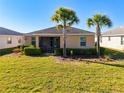 A well-maintained backyard with lush green grass, tropical palm trees, and a screened-in porch for outdoor relaxation at 17533 Timberline Pkwy, Punta Gorda, FL 33982