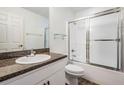 Bathroom with a vanity, granite counters, and a shower over tub with sliding glass doors at 2335 E Del Webb Blvd, Sun City Center, FL 33573