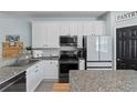 Bright kitchen featuring granite countertops, white cabinets, stainless steel appliances, and an adjacent pantry at 7240 102Nd Ln, Seminole, FL 33772
