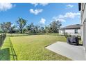 Large backyard features lush green lawn, mature trees, and a black grill on the patio at 9008 Waxwing Way, Parrish, FL 34219