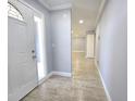 View of the open foyer with light gray walls and light wood-look tile floors flowing into the living spaces at 9308 Pinero St, Spring Hill, FL 34608