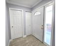 Bright foyer features wood-look tile flooring, neutral paint, and white doors with brass hardware at 9308 Pinero St, Spring Hill, FL 34608