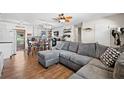 Open-concept living room featuring wood floors and a comfortable gray sectional couch with decorative pillows at 11114 Freedom Way, Seminole, FL 33772