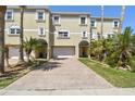 Inviting exterior of a multi-story home with a brick driveway, two-car garage, and lush tropical landscaping at 156 117Th Ave, Treasure Island, FL 33706
