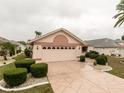 Charming single-story home with a two-car garage, complemented by manicured landscaping and patterned driveway at 1603 E Del Webb Blvd, Sun City Center, FL 33573