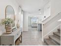 Bright foyer featuring tile floors, a stylish console table, and a staircase leading to the upper level at 16614 Mosaic Oar Dr, Wimauma, FL 33598