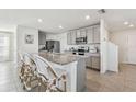 Modern kitchen boasting a granite island with seating, stainless steel appliances, and gray cabinets at 16614 Mosaic Oar Dr, Wimauma, FL 33598