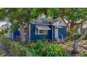 Quaint blue home with a well-manicured yard, featuring mature trees and landscaping at 1700 30Th N Ave, St Petersburg, FL 33713