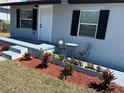 Inviting front yard with fresh mulch, colorful flowers, and a cozy bistro set on the porch at 1913 Park Ave, Tarpon Springs, FL 34689