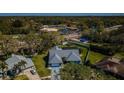 An aerial view of a well-maintained single-Gathering home featuring a screened-in pool and lush greenery at 2657 Crystal Circle Cir, Dunedin, FL 34698