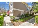 Exterior of a two-story townhome featuring a lush lawn, garden, and a concrete walkway at 11240 Windsor Place Circle Cir, Tampa, FL 33626