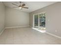 Bright living room featuring tile floors, neutral walls, a ceiling fan, and sliding glass doors to the outdoors at 1721 Sutton Pl, Dunedin, FL 34698