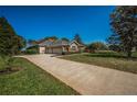 Sprawling property featuring an expansive driveway, a three-car garage, and lush green landscaping at 19719 Prince Benjamin Dr, Lutz, FL 33549