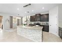 Open-concept kitchen featuring dark cabinets, granite countertops, and a large center island with a tile backsplash at 3097 Storybrook Preserve Dr, Odessa, FL 33556