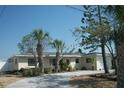 Charming single-story home with a light-colored exterior, garage, and a driveway, surrounded by mature trees at 390 Belle Point Dr, St Pete Beach, FL 33706
