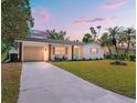 Charming single-story home featuring a lush lawn, attached garage, and a welcoming turquoise-colored front door at 5314 13Th S Ave, Gulfport, FL 33707