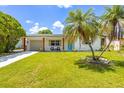 Inviting home featuring a lush green lawn, palm trees, and a cheerful blue front door at 5314 13Th S Ave, Gulfport, FL 33707