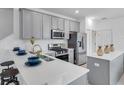 Modern kitchen with stainless steel appliances, grey cabinets, white countertops, and barstool seating at 5728 Skytop Dr, Lithia, FL 33547