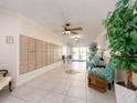 Condo lobby with mailboxes, tile flooring, comfortable seating, and a decorative potted plant at 100 Bluff View Dr # 317A, Belleair Bluffs, FL 33770