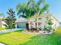Inviting home showcasing lush landscaping, including palm trees and green grass, complemented by a two-car garage at 10105 Paradise Fish Dr, Riverview, FL 33578