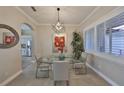 Elegant dining room with modern chandelier, glass table and chairs, and view to kitchen at 1123 Signature Dr, Sun City Center, FL 33573