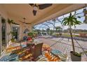 Spacious screened-in lanai with brick flooring, ceiling fans, dining set and seating, overlooking the lake at 1123 Signature Dr, Sun City Center, FL 33573