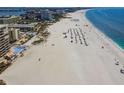 Scenic beach view featuring white sand, clear blue water, lounge chairs, and beach umbrellas at 11605 Gulf Blvd # 404, Treasure Island, FL 33706