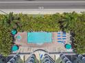 Aerial view of a pool and jacuzzi surrounded by palm trees, lounge chairs, and umbrellas at 11605 Gulf Blvd # 404, Treasure Island, FL 33706