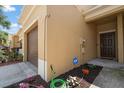 Corner view of townhome featuring ADT security sign, brown door, and colorful flowerbed along walkway at 2011 Hawks View Dr, Ruskin, FL 33570