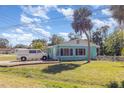 One-story home with light blue exterior, white trim, green grass and palm trees at 311 Ravenna N St, Nokomis, FL 34275