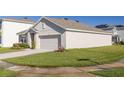Well-maintained single-story home with a neutral-colored exterior, a two-car garage, and green lawn at 31399 Penny Surf Loop, Wesley Chapel, FL 33545