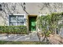 Inviting villa entrance with a bright green front door, manicured bushes, and window accents at 34907 Double Eagle Ct, Zephyrhills, FL 33541