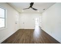 Bright living room features wood-look flooring, neutral paint, a ceiling fan, and a white front door at 3710 W Griflow St, Tampa, FL 33629