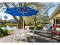 Inviting outdoor patio featuring a dining set under a large blue umbrella, overlooking a tranquil lake at 412 Pinewood Dr, Oldsmar, FL 34677