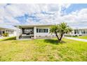 Inviting mobile home with a screened-in porch, palm tree, and manicured lawn in a friendly community at 4618 Newcomb Ave, Zephyrhills, FL 33541