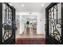 Elegant foyer with custom iron doors, wood floors, and views into the spacious living areas at 517 Belle Isle Ave, Belleair Beach, FL 33786