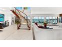 Bright living room with a curved staircase, white sofa, open layout, and scenic water views through large windows at 520 Belle Isle Ave, Belleair Beach, FL 33786