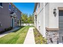 The townhouse's backyard has a grassy lawn with a concrete path between houses and nice landscaping at 6867 Citrus Creek Ln, Tampa, FL 33625