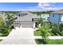 Aerial view of a two-story home with three car garage, paver driveway and water views at 14610 Red Castle Ave, Lithia, FL 33547