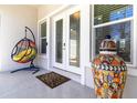 Inviting front porch with a hanging chair, decorative jar, and double-door entry at 2202 Yalta Ter, North Port, FL 34286