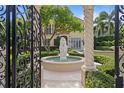 View through iron gate to garden with fountain, manicured hedges, and Mediterranean-style home at 608 Orange Ave, Clearwater, FL 33756