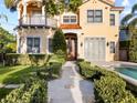 Elegant two-story home featuring a red tile roof, stucco exterior, and lush landscaping with a pristine pool at 608 Orange Ave, Clearwater, FL 33756