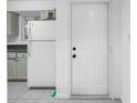 Kitchen entrance, featuring light tile flooring, a white refrigerator, and wood cabinets at 6826 Stones Throw N Cir # 11104, St Petersburg, FL 33710