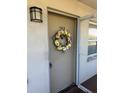 Unit 302 entryway featuring a tan door decorated with a yellow flower wreath and a black exterior light fixture at 8100 Dr Martin Luther King Jr N St # 302, St Petersburg, FL 33702